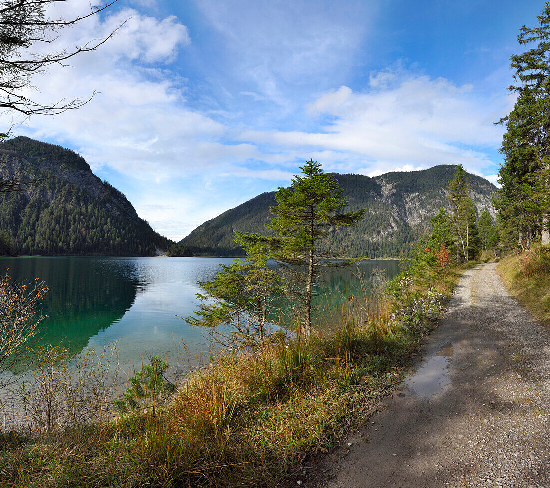 Landschaft eines Weges neben einem klaren See im Herbst, Plansee, Tirol, Österreich