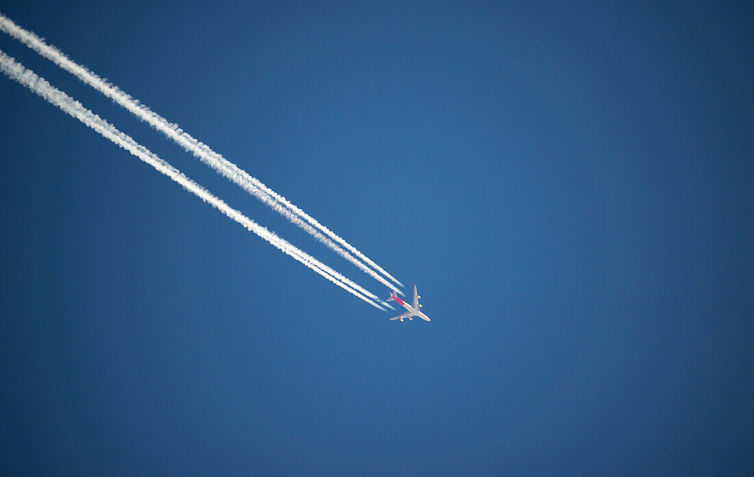 Airplane and contrails against blue sky, Canada