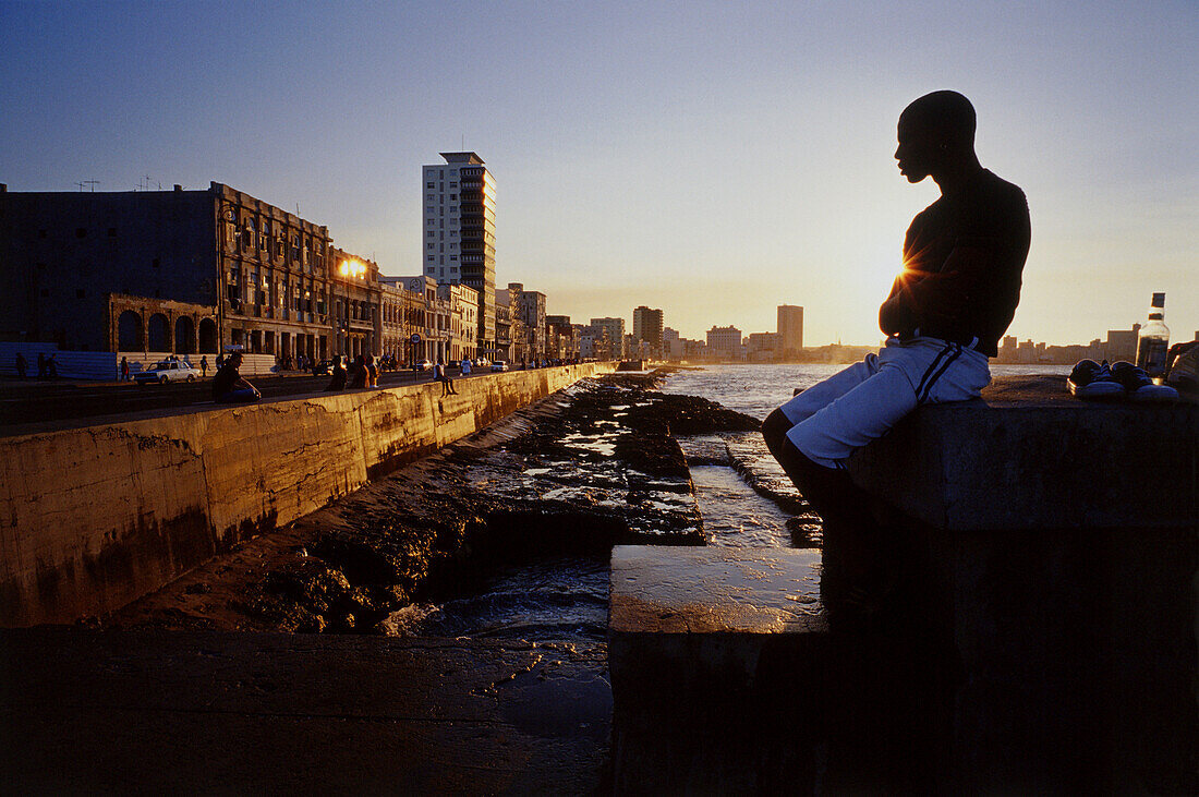 Mann am Wasser sitzend bei Sonnenuntergang Malicon, Havanna, Kuba
