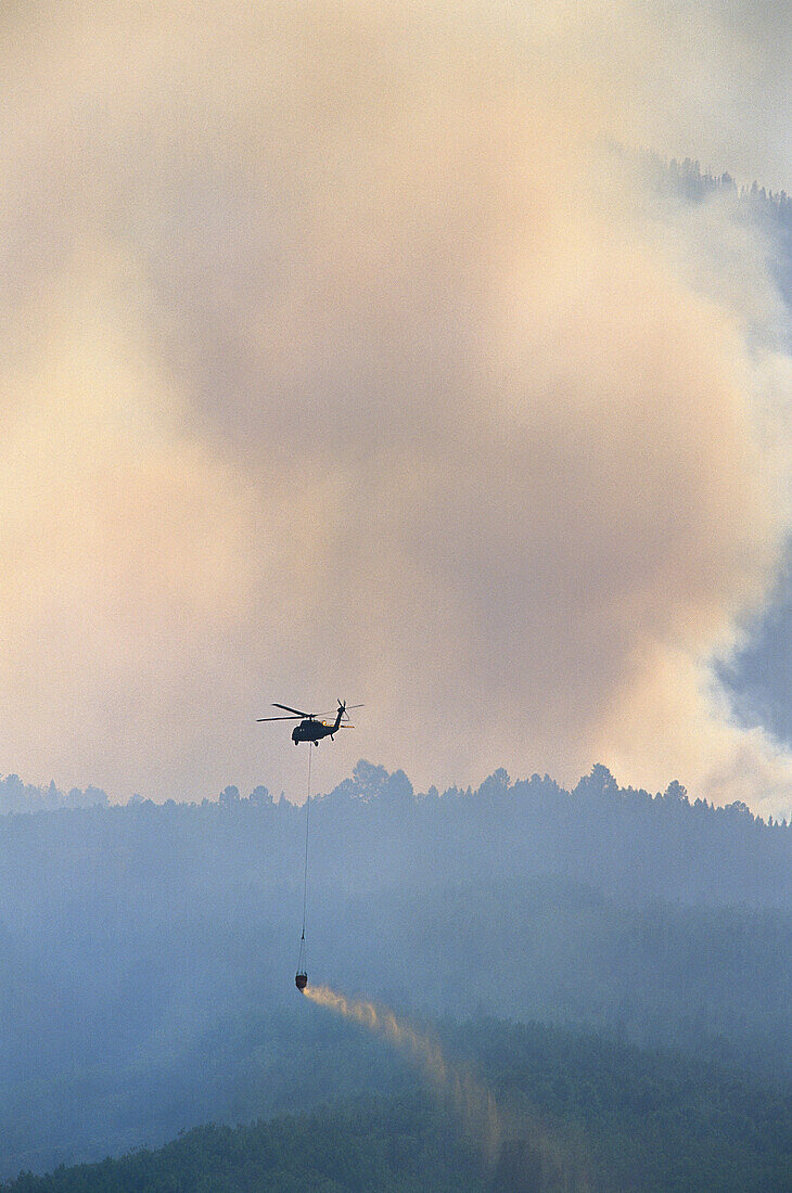 Rauch eines Waldbrandes mit Löschhubschrauber