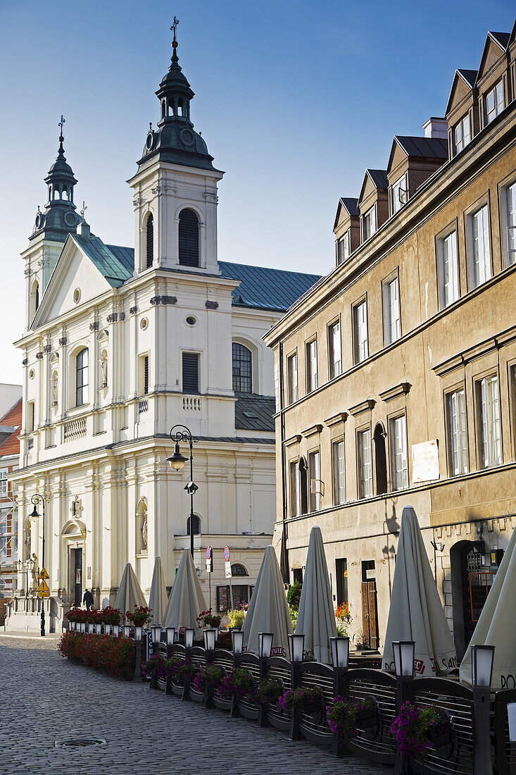 Street scene with Church of the Holy Spirit and restaurant patio, Old Town, Warsaw, Poland.