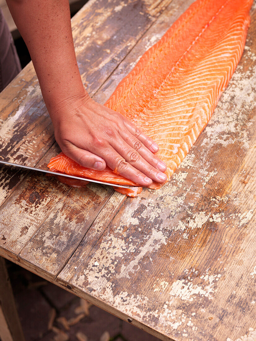 Person schneidet Fisch in Scheiben