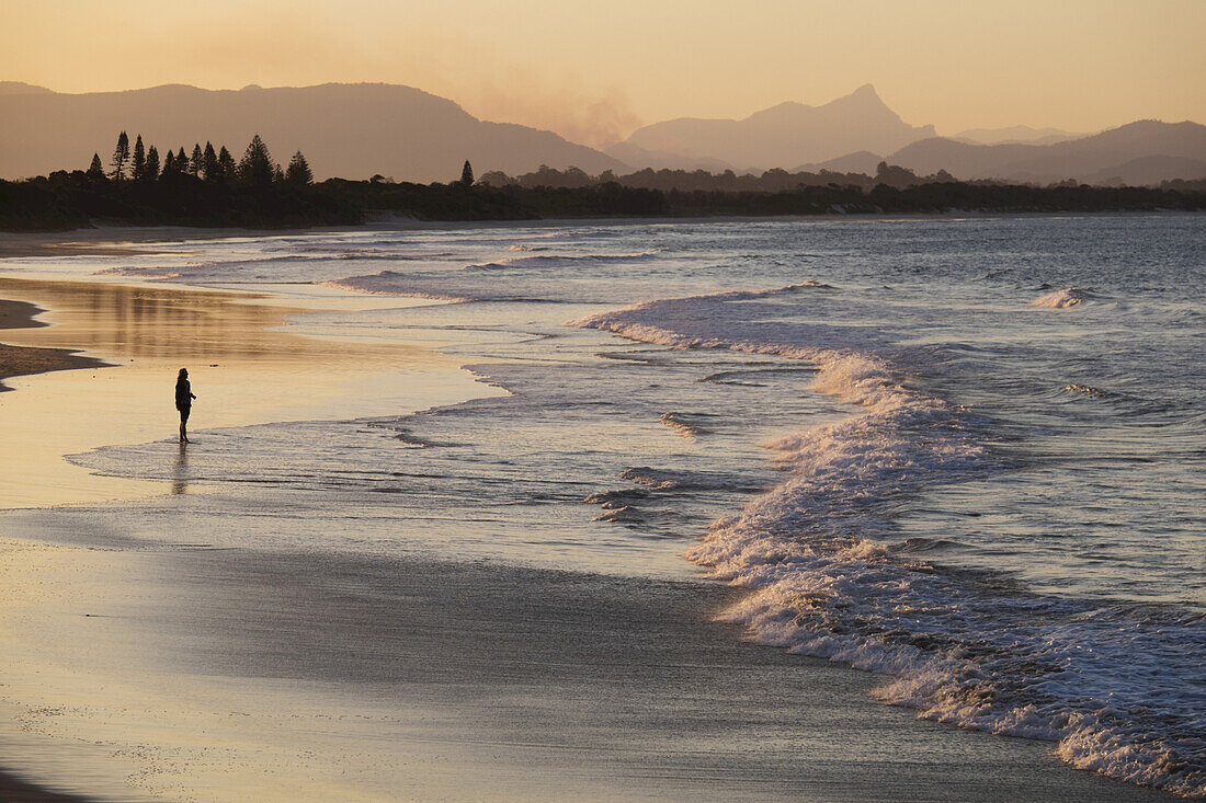 Silhouette of person on beach watching the waves hitting the shore at Byron Bay in New south Wales, Australia