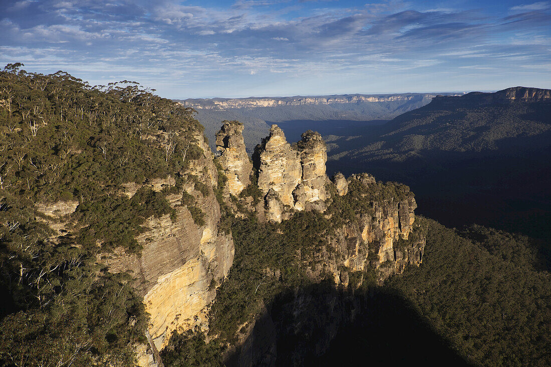Sonnenlicht, das sich in den Felsformationen der Three Sisters spiegelt, und eine malerische Aussicht auf den Blue Mountains National Park in New South Wales, Australien