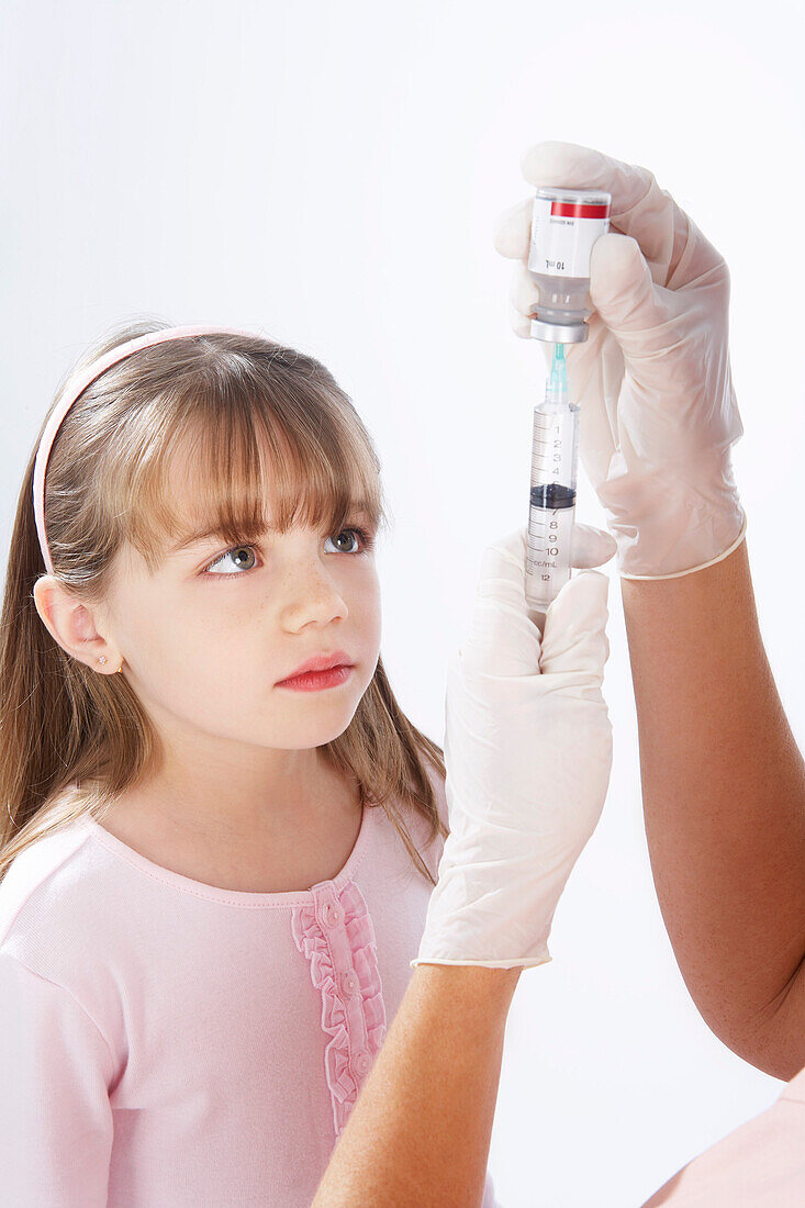 Kleines Mädchen beobachtet Krankenschwester beim Vorbereiten einer Nadel