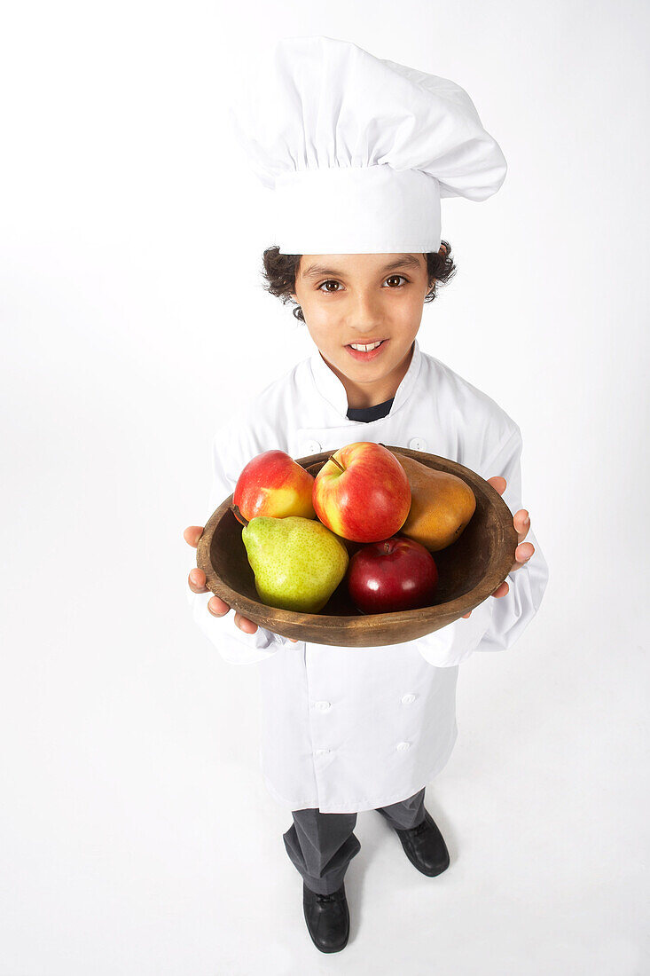 Junge als Koch verkleidet hält Schale mit Obst