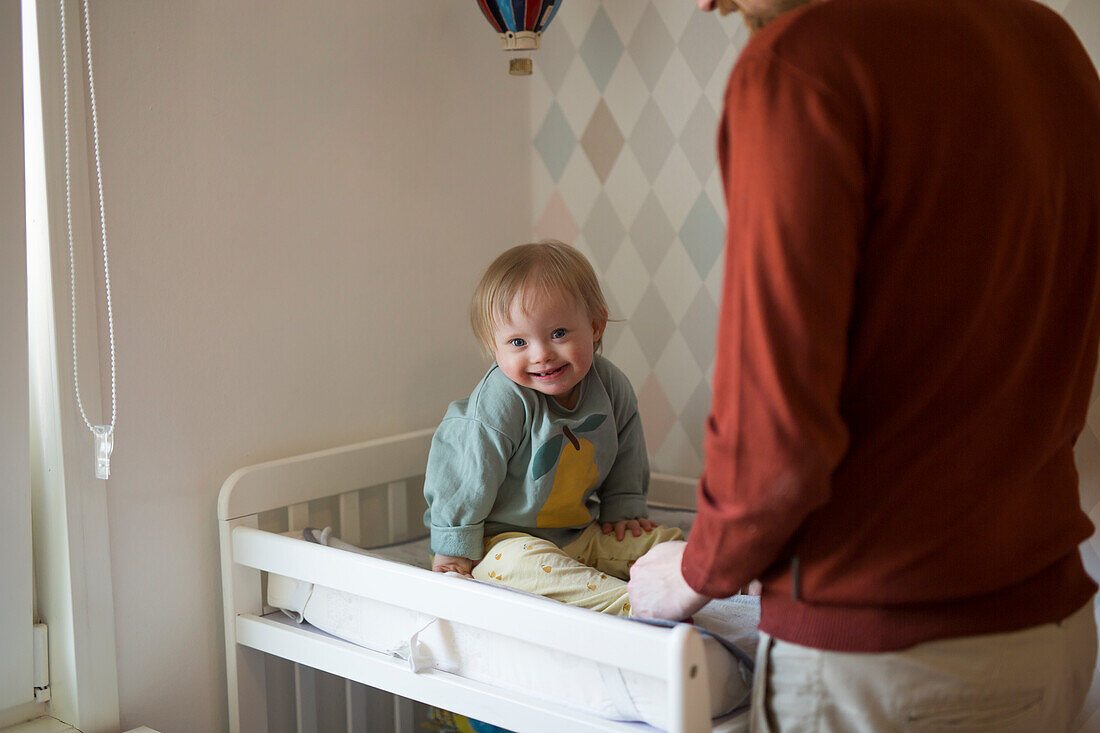 Toddler with down syndrome sitting on changing table