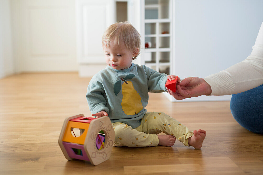 Mutter und Kleinkind mit Down-Syndrom beim Spielen