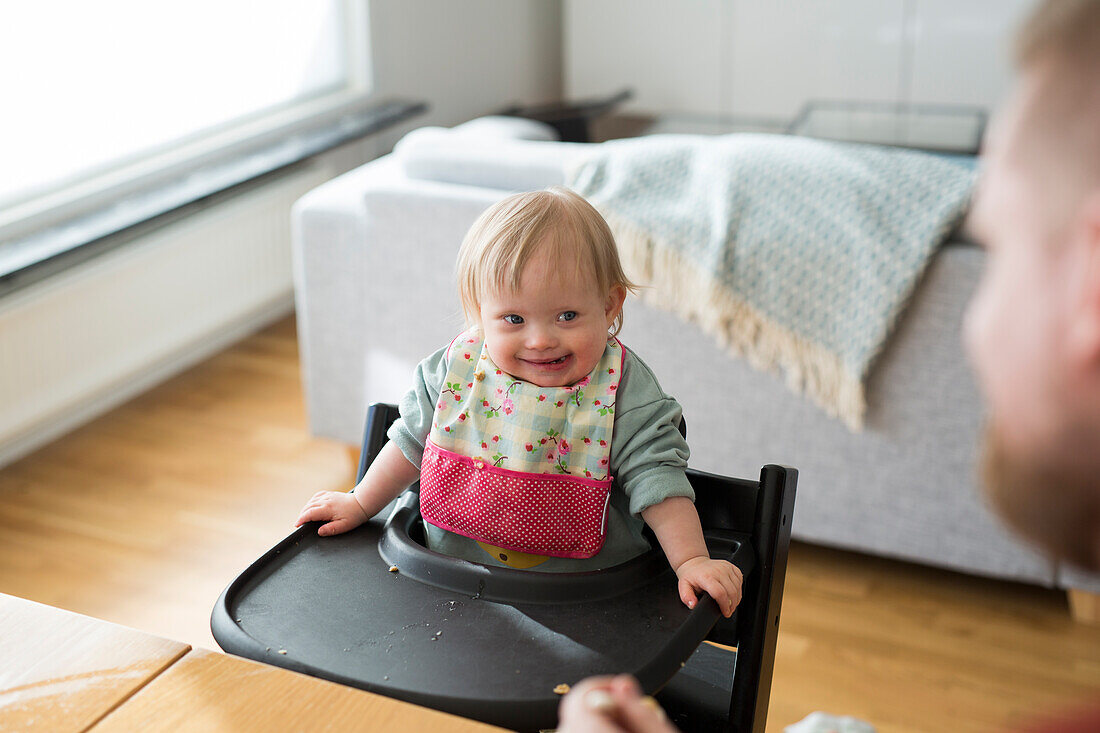 Toddler with down syndrome sitting on high chair