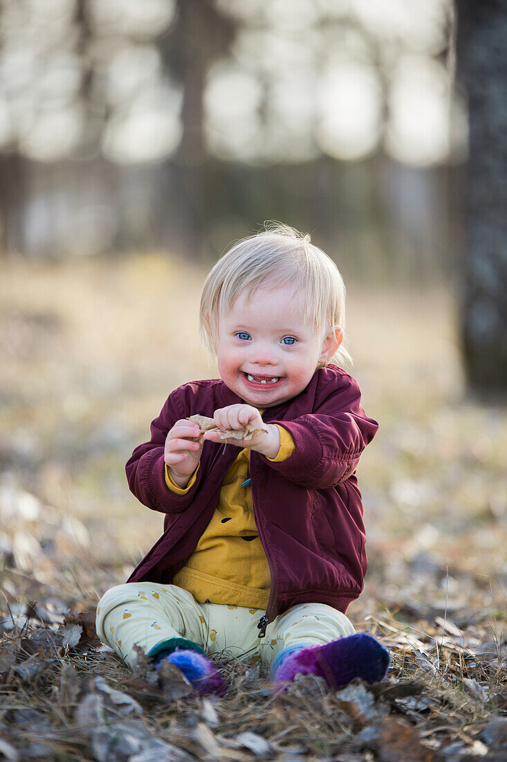 Lächelndes Kleinkind mit Down-Syndrom schaut in die Kamera