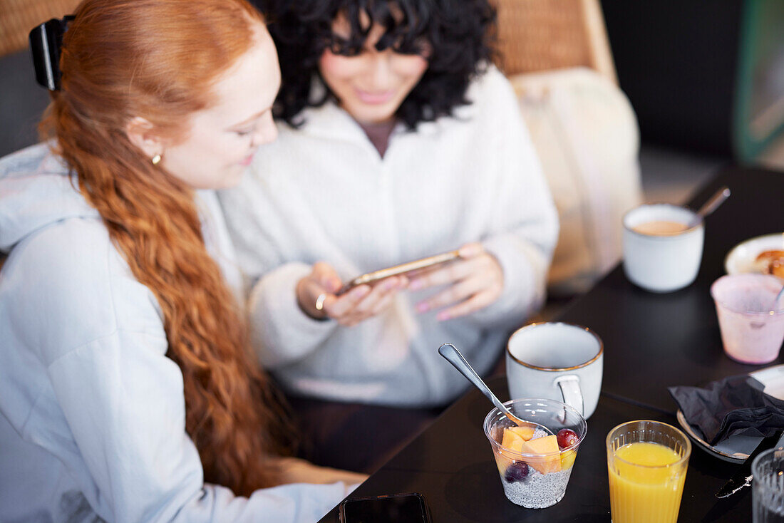 Junge Frau telefoniert und schaut sich ein Video im Cafe an