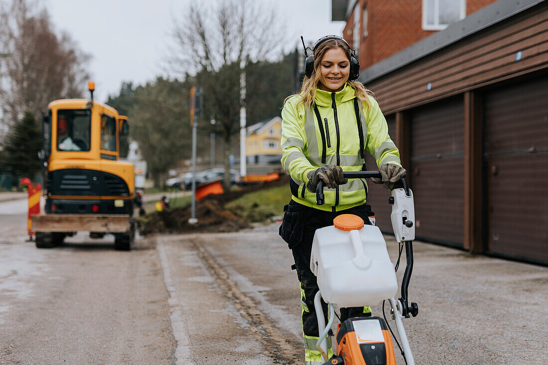 Female road worker operating machinery