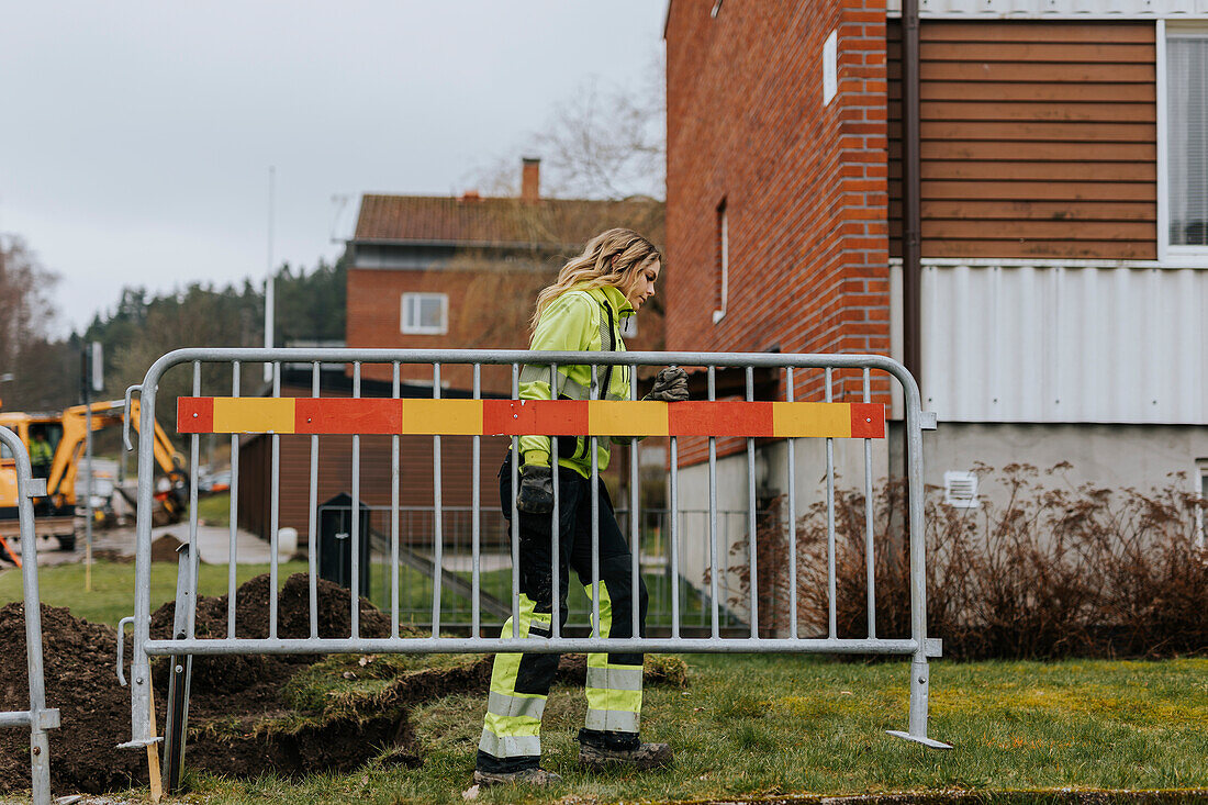 Straßenbauarbeiterin installiert Verkehrsschranke