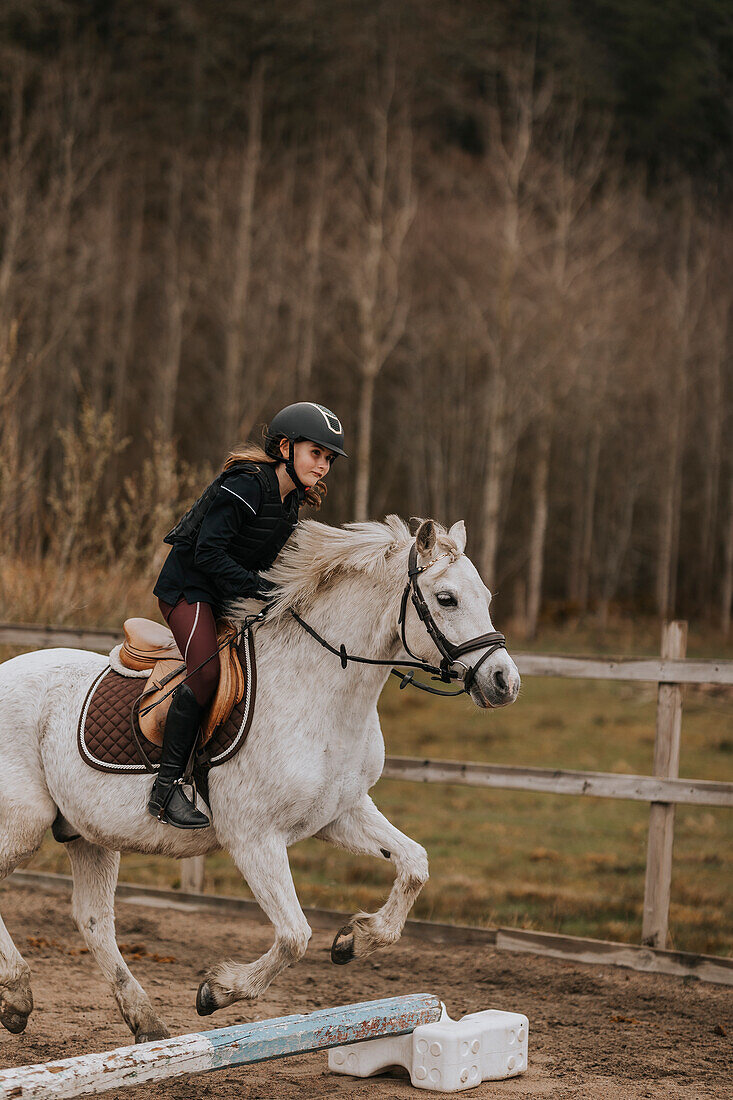 View of girl horseback riding