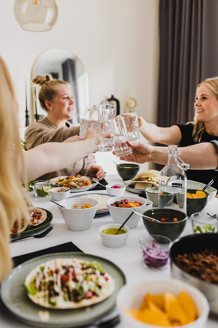 Group of friends raising toast during Mexican feast