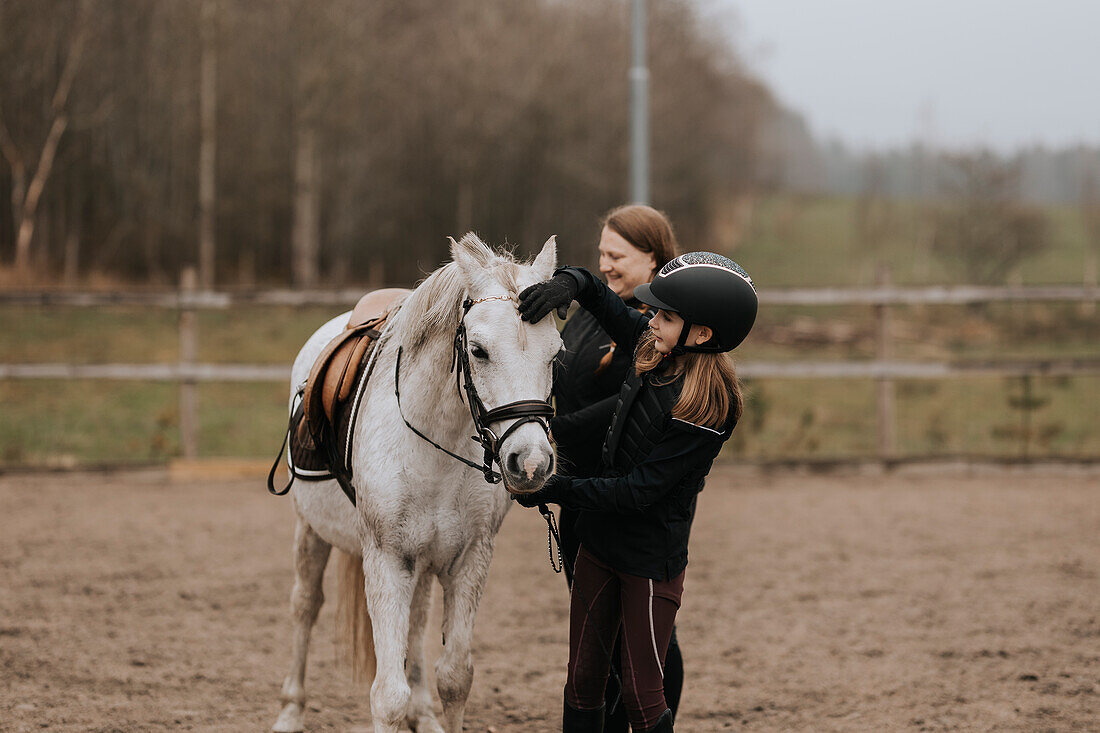 Smiling girl standing with horse and looking at camera