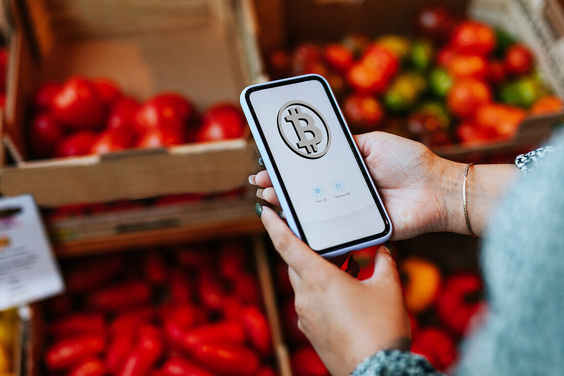 Woman paying with bitcoin crypto currency for groceries