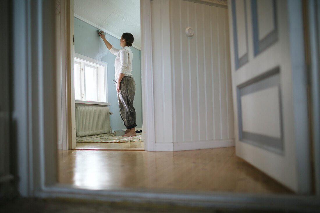 Frau streicht Wand zu Hause