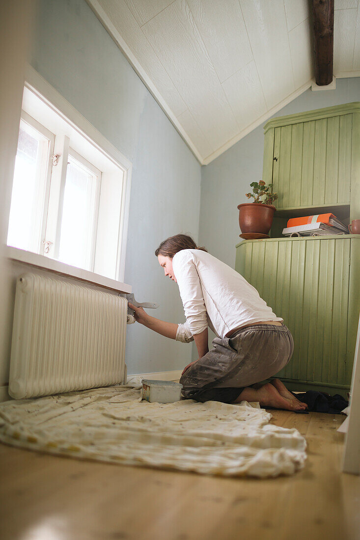 Frau streicht Wand zu Hause