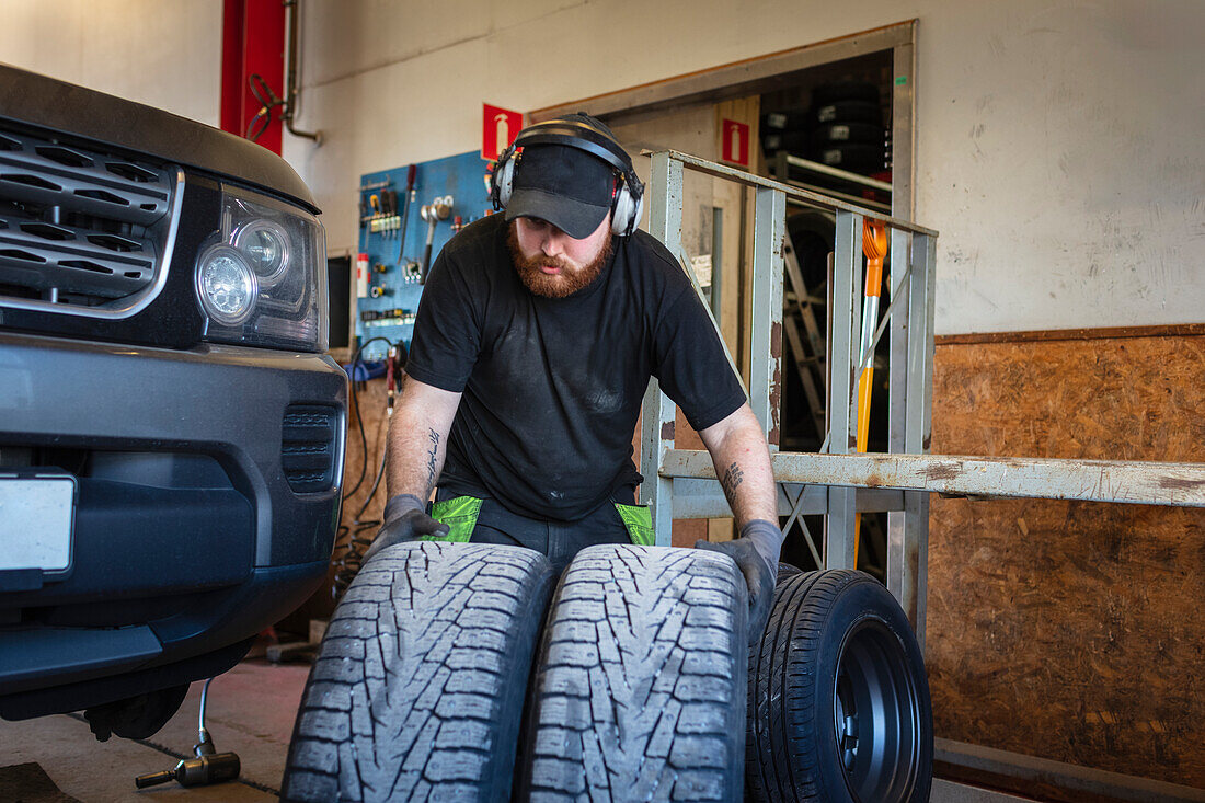 Mechaniker in Garage hält Reifen