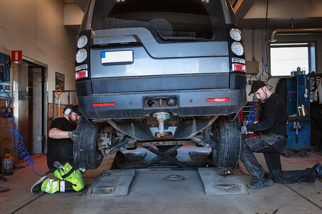 Mechanics in garage changing tires on car