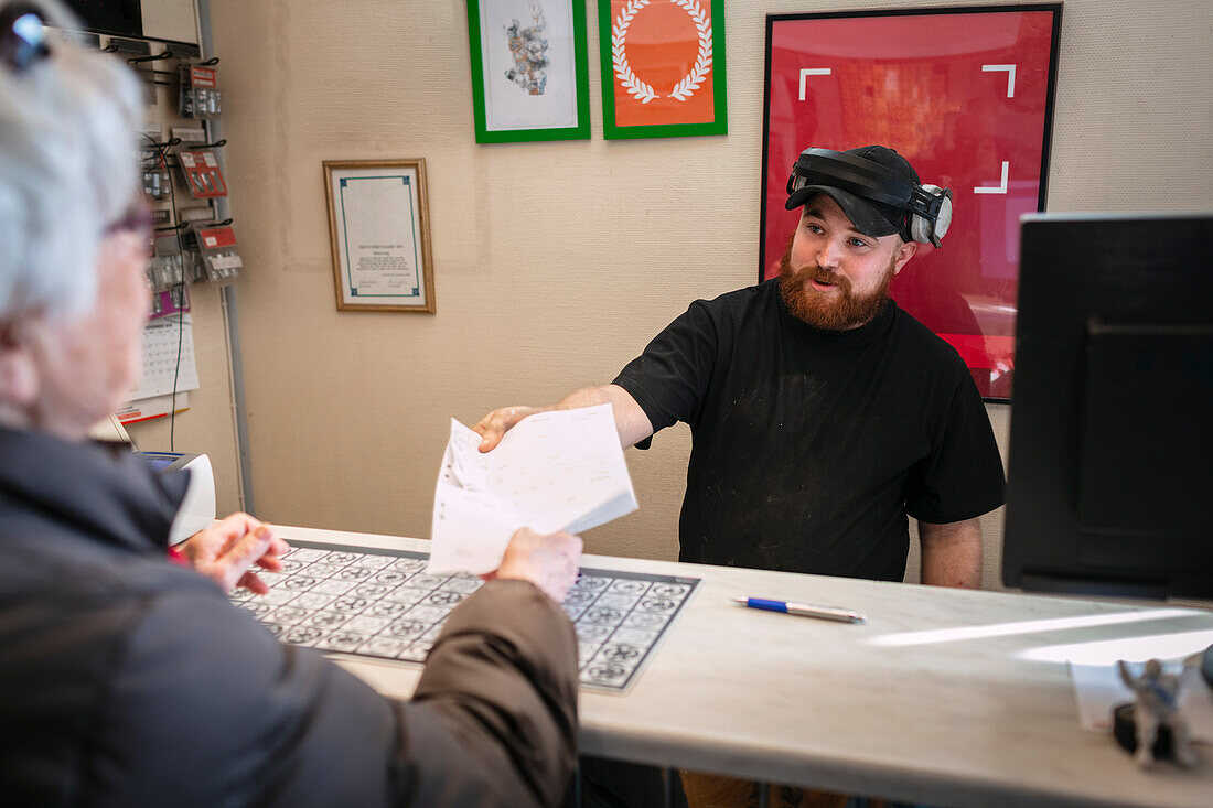 Mann gibt Kundin Rechnung für Reifenwechsel in Werkstatt