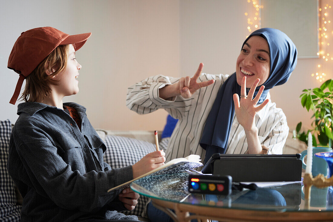 Mutter mit Hijab hilft Sohn mit ADS oder ADHS bei den Mathe-Hausaufgaben
