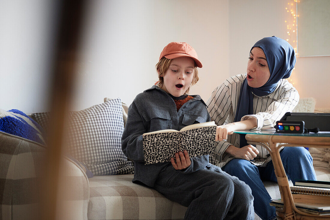 Mutter mit Hidschab hilft Sohn bei den Hausaufgaben