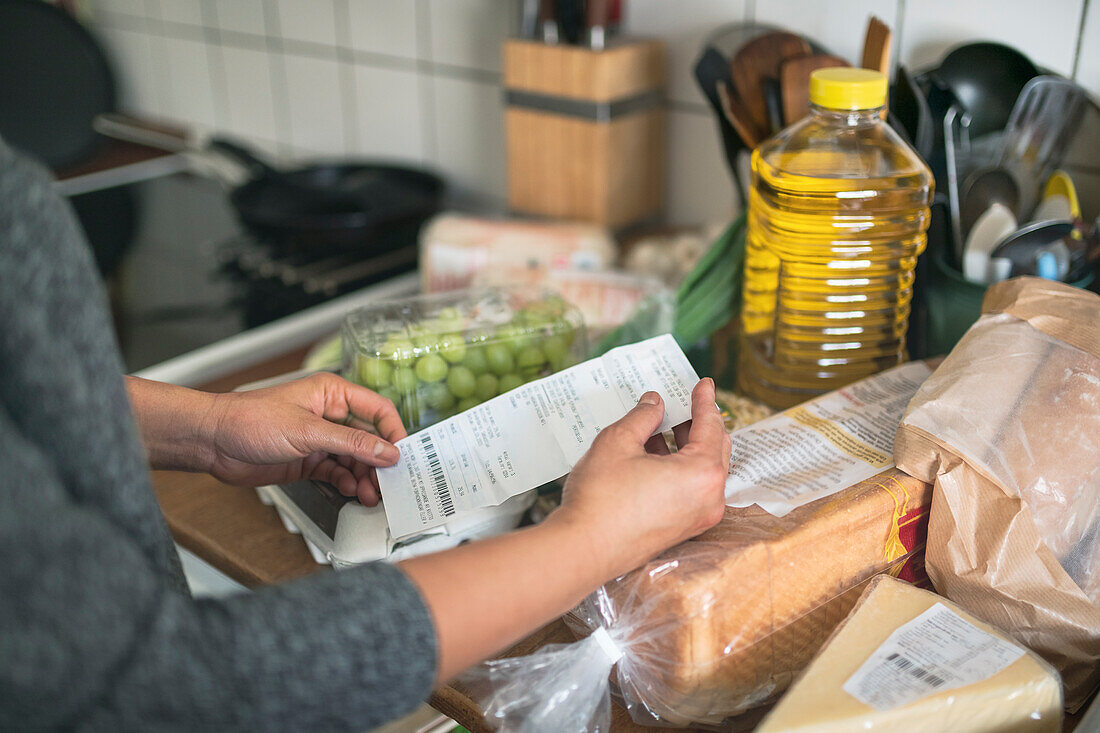 Person prüft Kassenzettel im Supermarkt während der Inflation mit Preissteigerungen bei Lebensmitteln und Konsumgütern
