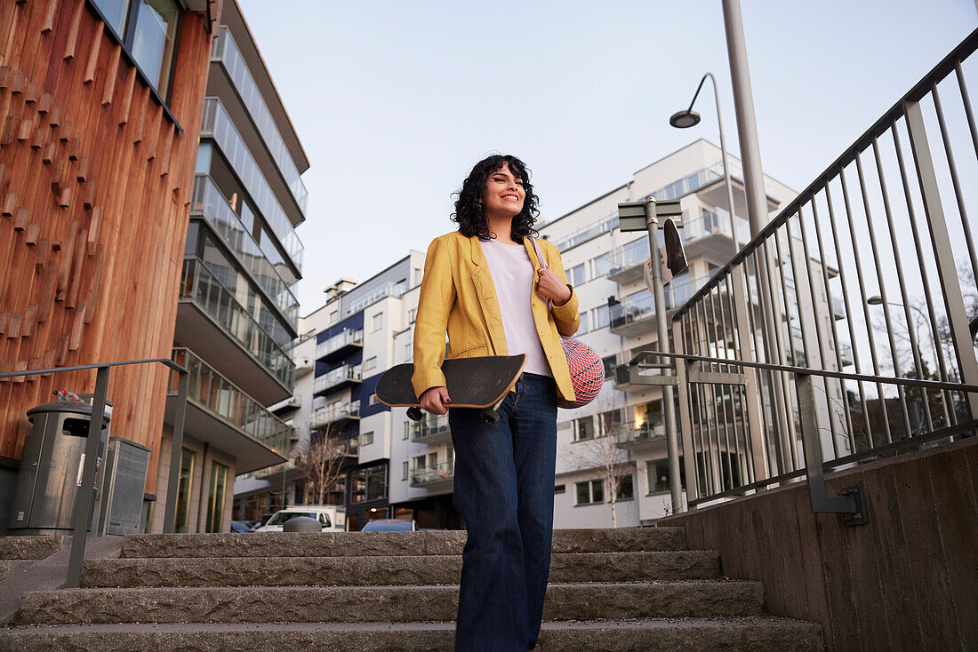 Low angle view of woman walking down stairs and carrying skateboard