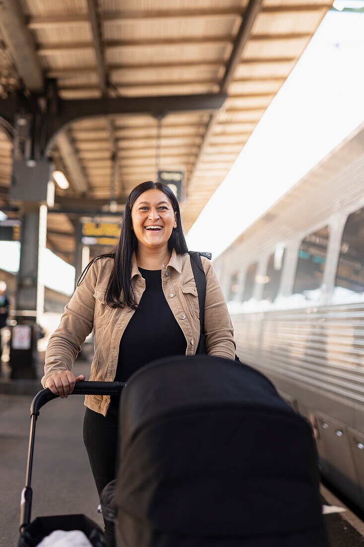 Mid adult woman at train station pushing pram