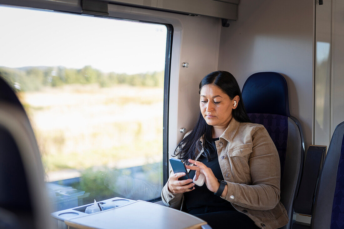 Mittlere erwachsene Frau im Zug telefoniert mit Handy