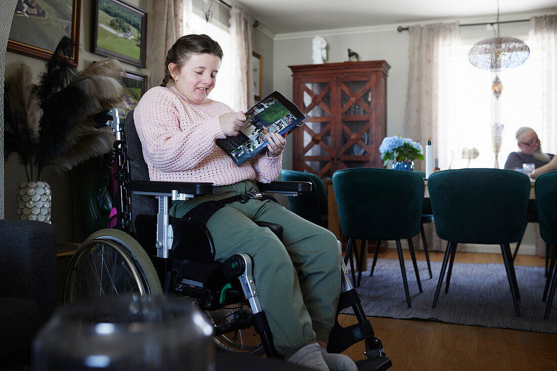 Behindertes Mädchen im Teenageralter liest Zeitschrift im Wohnzimmer