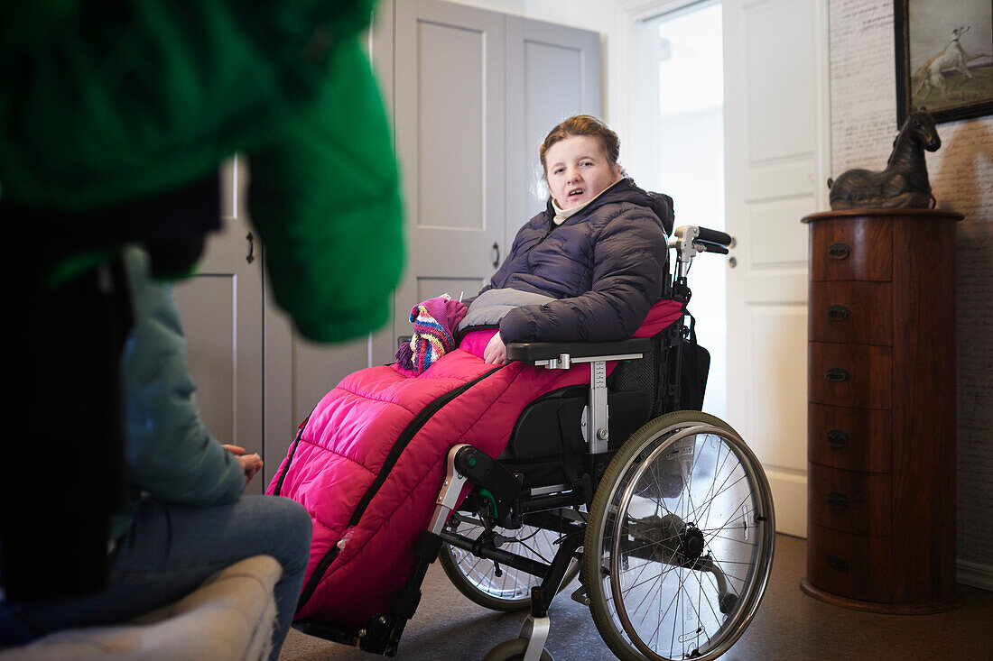 Disabled teenage girl sitting on wheelchair at home