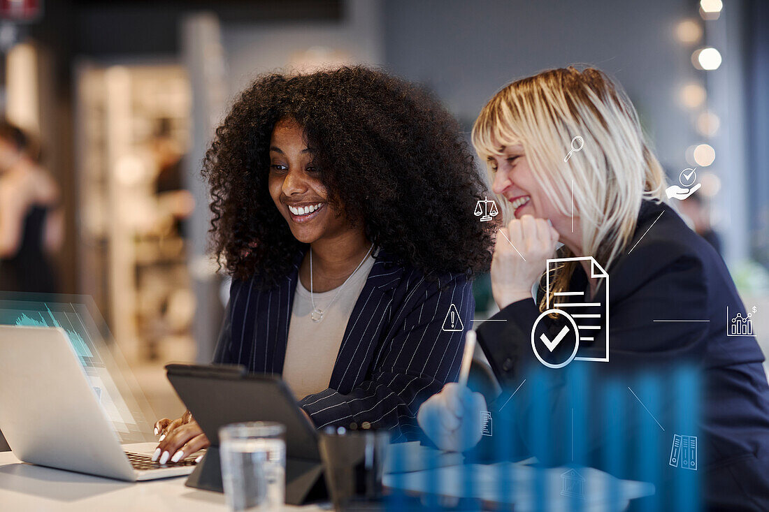 Smiling women in office using laptop together