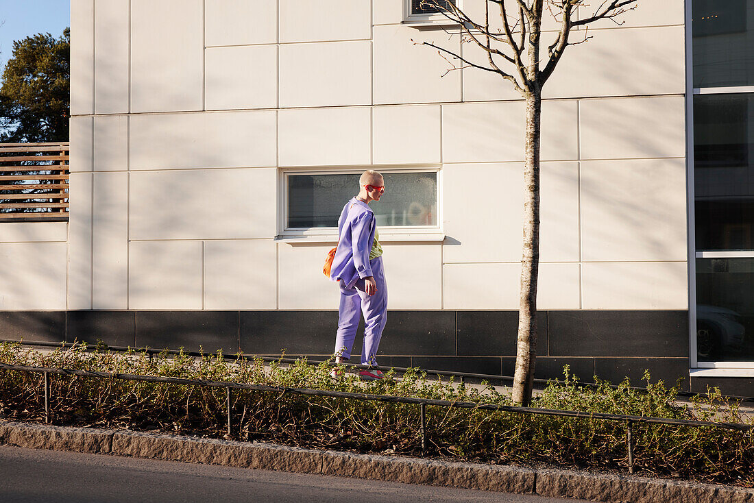 Blick auf eine junge Frau beim Skateboardfahren, modernes Gebäude im Hintergrund