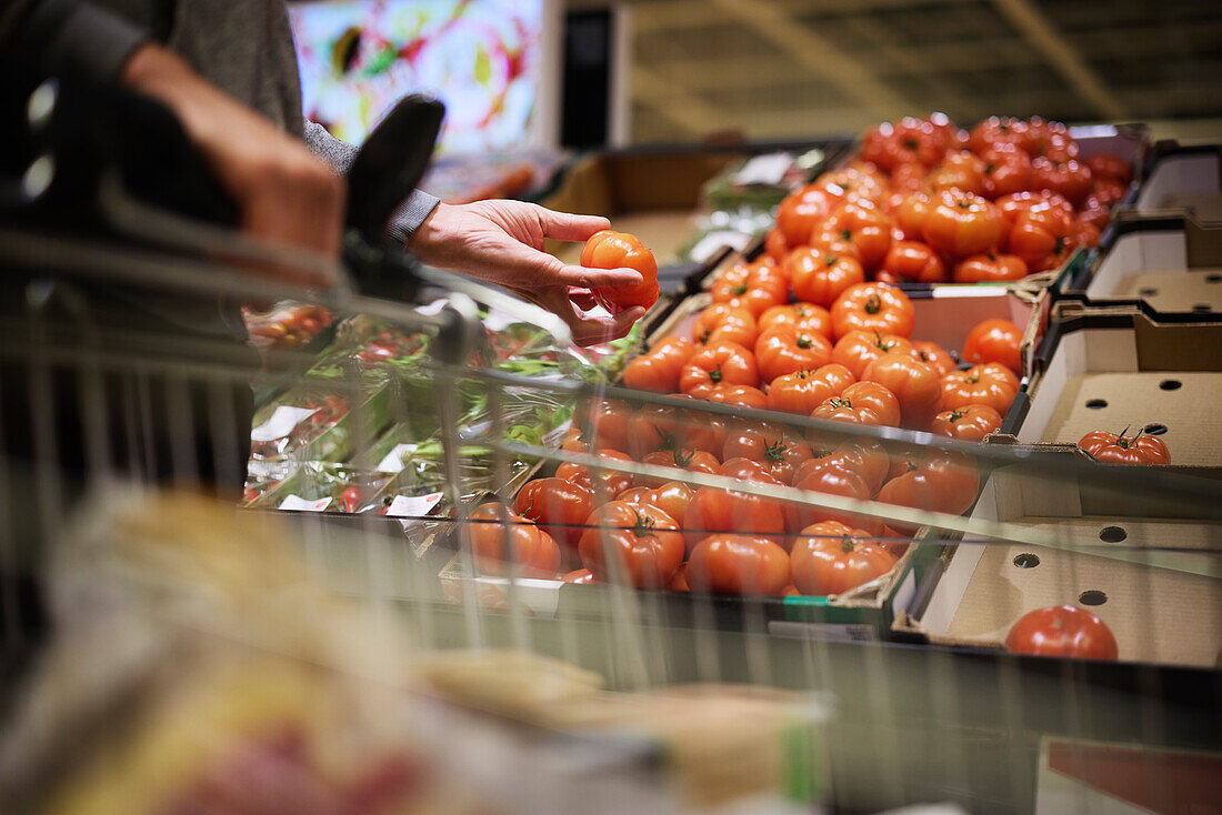 Kundenhand hält Beefsteak-Tomate im Laden
