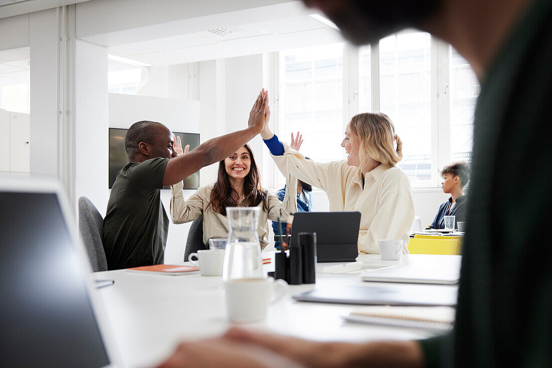 Group of business people high-five during business meeting in office