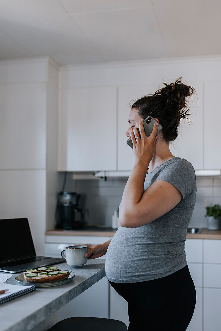 Pregnant woman talking on phone while working from home