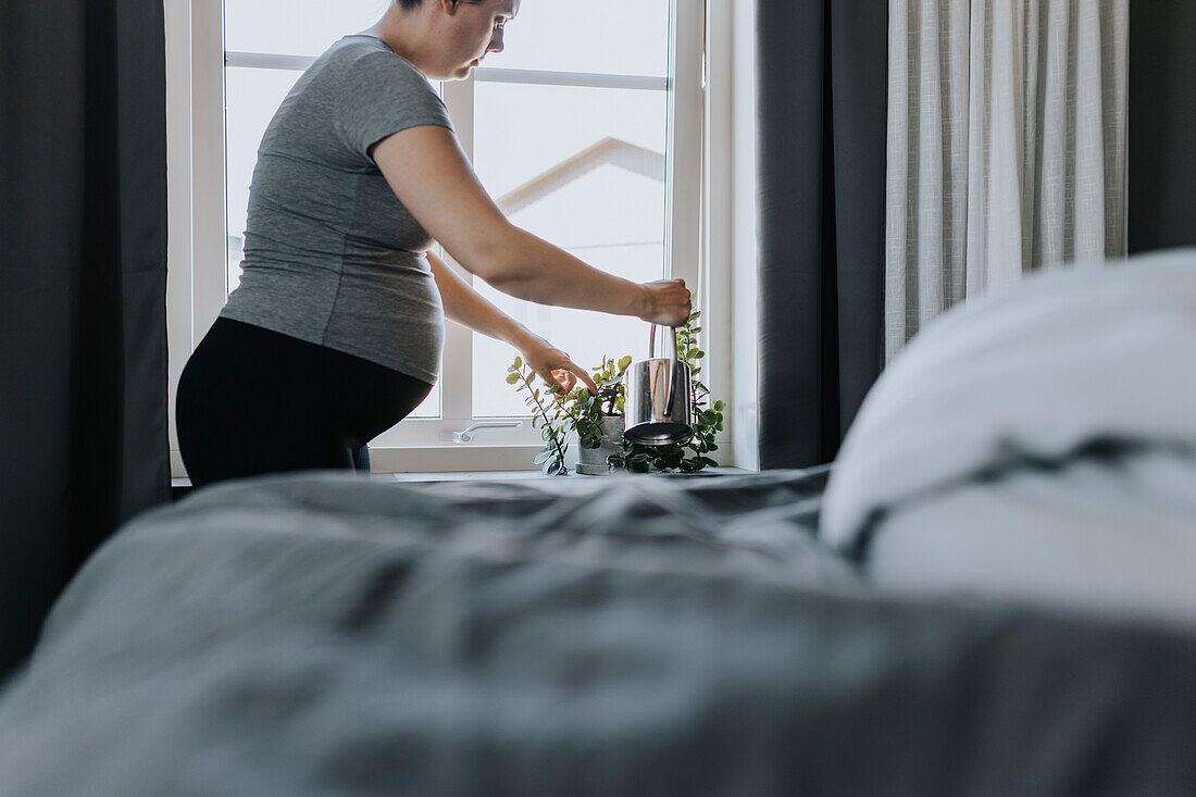 Pregnant woman doing housework and watering plants