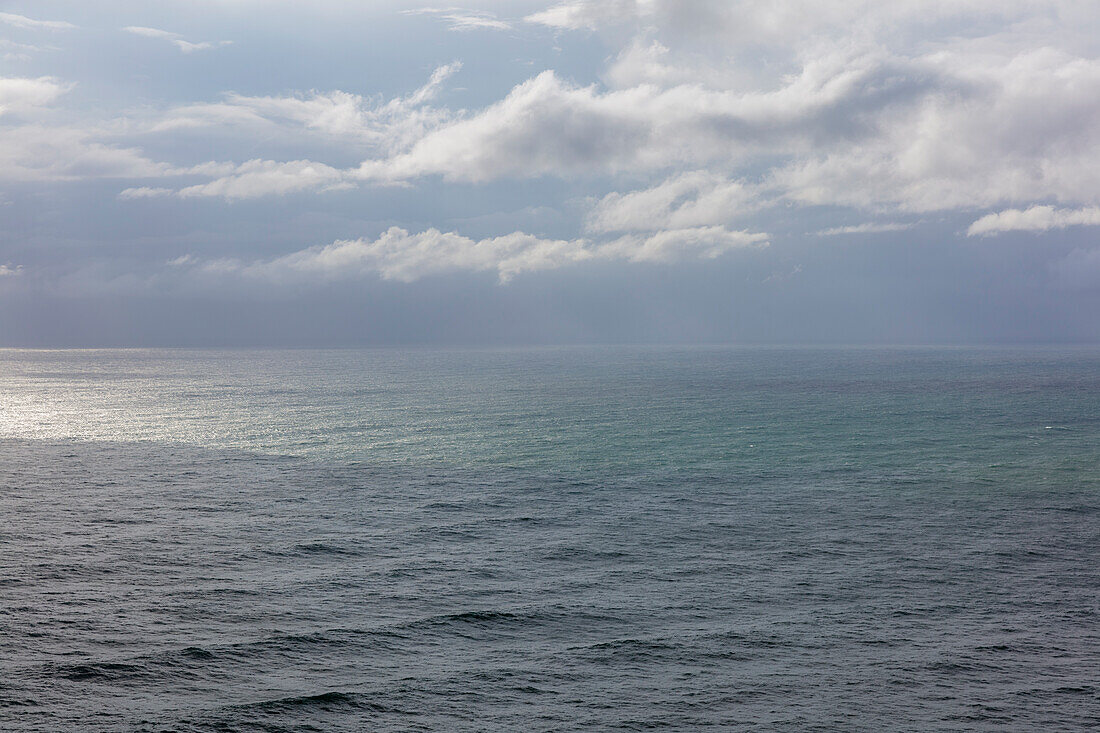 Storm clouds over the Pacific ocean at dusk, green and grey water surface, rain shower and rain cloud.