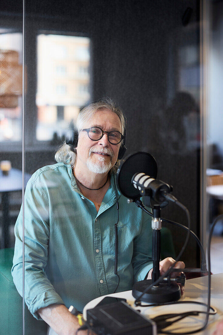 Mature man sitting and hosting podcast or radio show or podcast