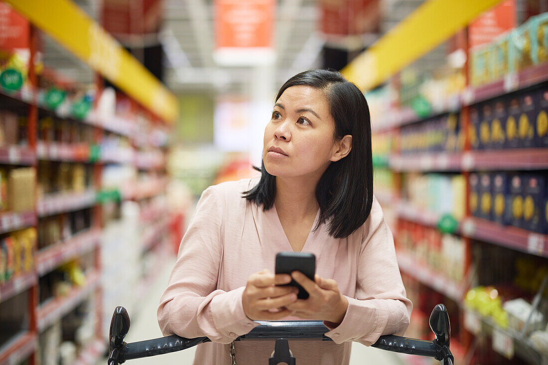 Woman looking at prices during inflation while doing shopping in supermarket