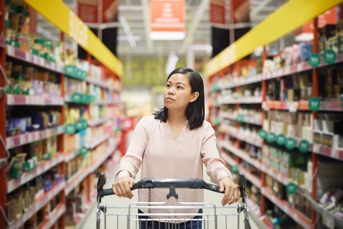 Frau schaut beim Einkaufen im Supermarkt auf die Preise während der Inflation