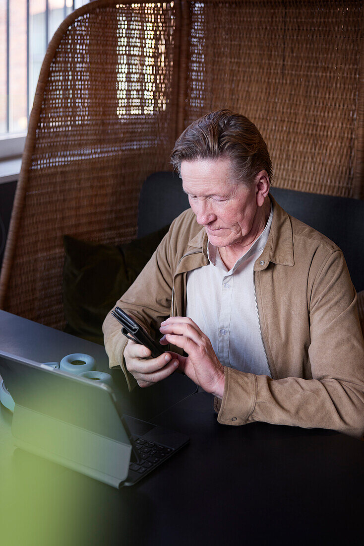 Älterer Mann mit Telefon und Tablet