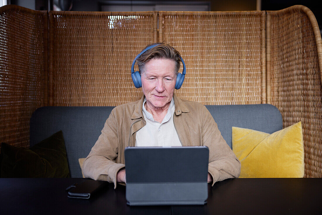 Senior man with headphones using tablet