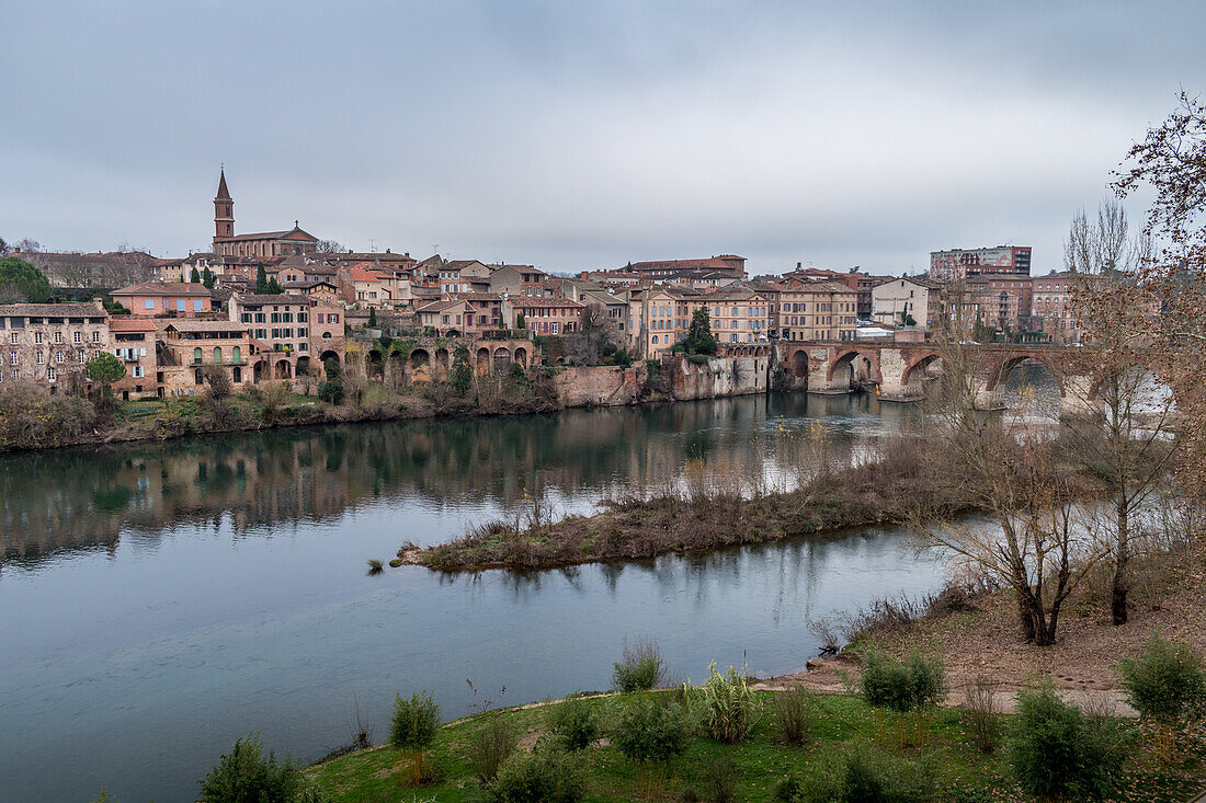 View of Albi, the city and historic buildings from the River Tarn, the Pont Vieux and an island in the stream. 