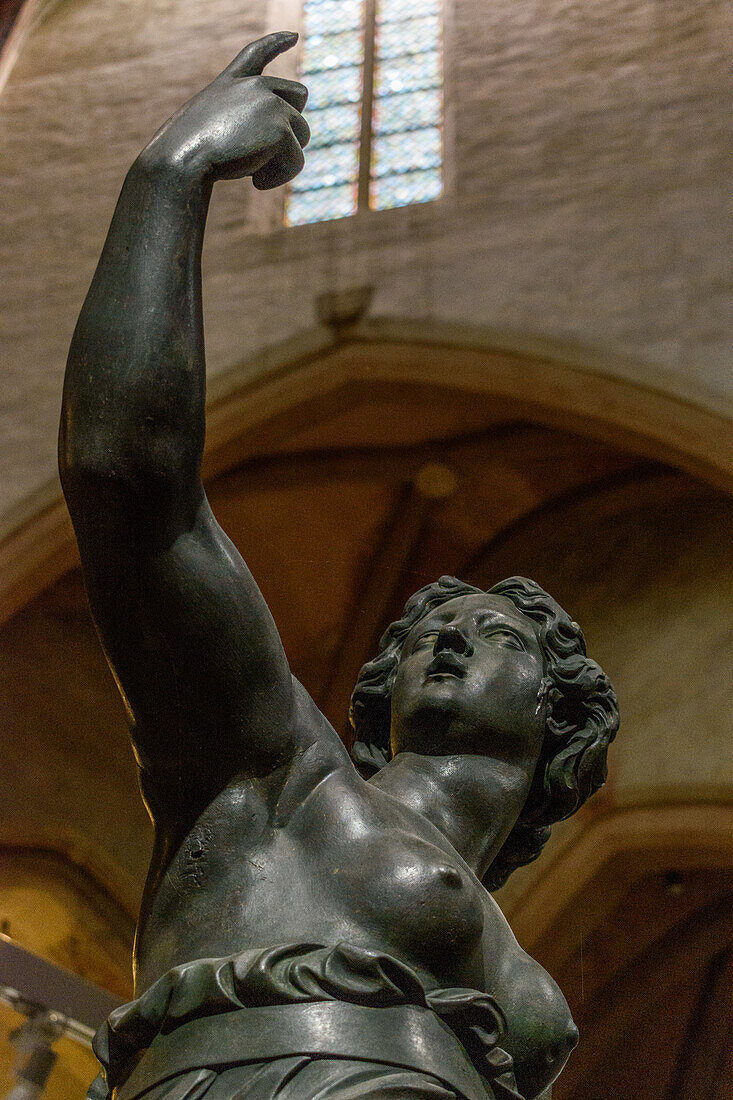 Interior of a museum. A statue of a woman with her arm raised. 