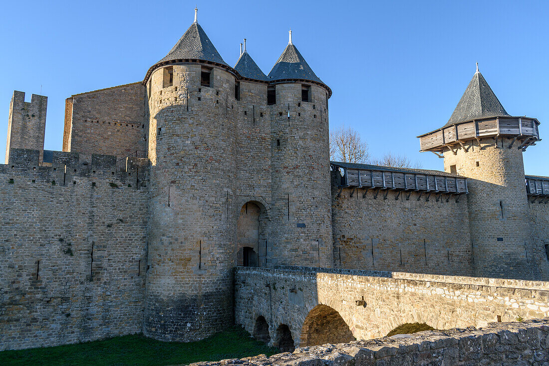 The Château Comtal, Count’s Castle, is a medieval castle in the Cité of Carcassonne, tall towers and wall, and a bridge to a fortified gate. 