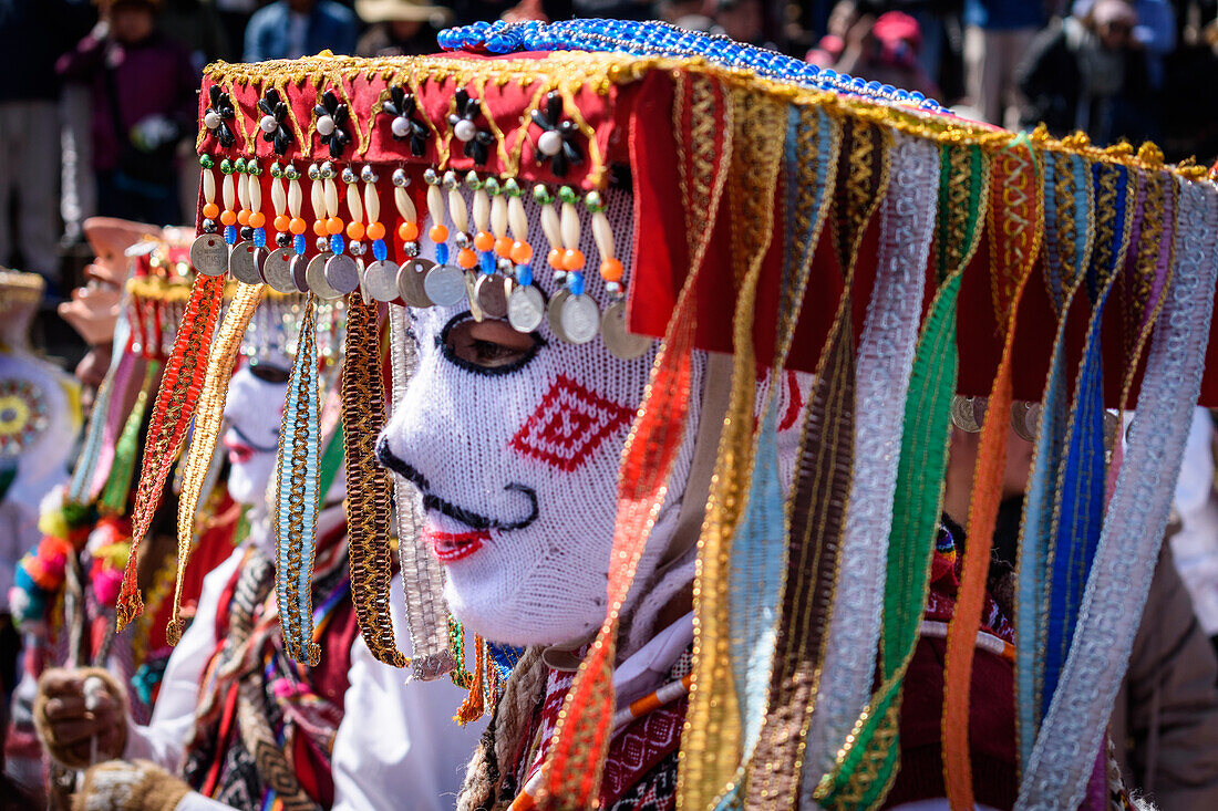 Cusco, a cultural fiesta, people dressed in traditional colourful costumes with masks and hats, brightly coloured streamers. 